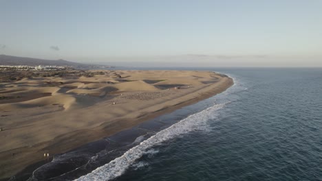 Empty-sand-beach-with-beautiful-dunes-and-waves-crashing-at-the-coastline