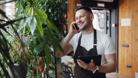 slow motion of flower shop manager talking on mobile phone and using tablet