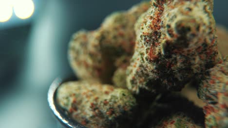 un zoom en macro cinematográfico toma detallada de una planta de cannabis, variedades híbridas, indica y sativa, flor de marihuana, en un soporte giratorio de 360, grito brillante negro, cámara lenta, video 4k, iluminación de estudio