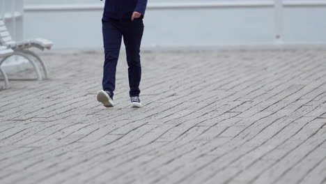 a woman in sneakers is walking across the pier in slow motion