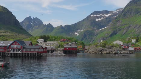 scenic view of red houses in å village, lofoten, surrounded by majestic mountains and clear waters