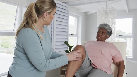 caucasian female physiotherapist checking knee of senior woman, copy space, slow motion