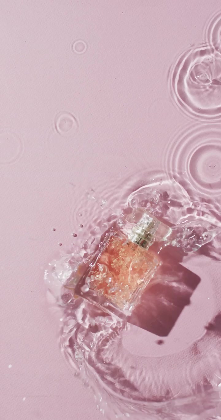 Video verticale di flacone di prodotto di bellezza in acqua con spazio per il testo su sfondo rosa