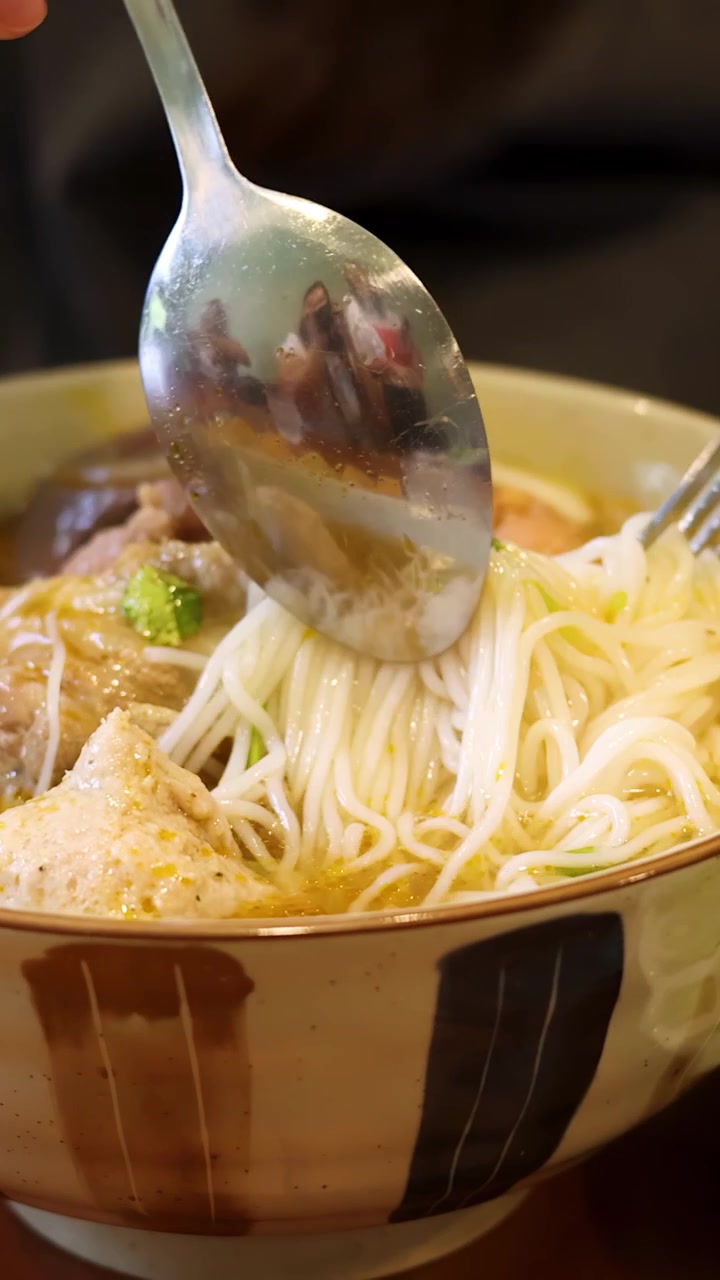 Cận cảnh đôi tay dùng nĩa và thìa để ăn phở bò truyền thống Việt Nam