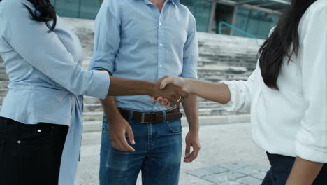 manager and her assistant shaking hands with job applicant outside the business building