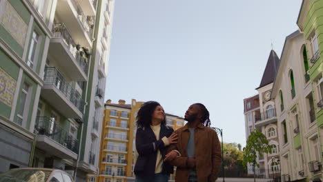 una pareja feliz buscando edificios juntos caminando por una zona residencial moderna y tranquila.