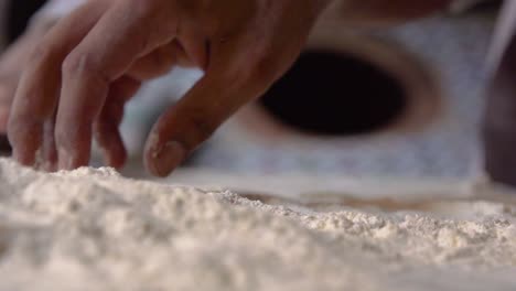 dough and flour being picked up and rolled by master baker in traditional bakery in slow motion