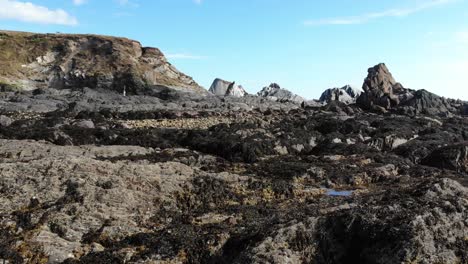 Aerial-Low-Flying-Over-Rugged-Shoreline-Rocks-At-Thurlestone-In-South-Devon-During-Low-Tide