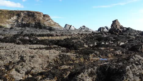 vuelo aéreo bajo sobre rocas escarpadas de la costa en thurlestone en el sur de devon durante la marea baja
