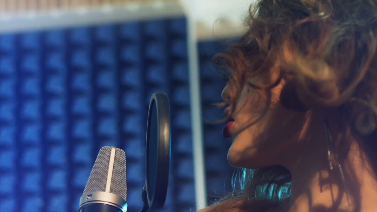 Young female singer recording album in the professional recording studio. Slow motion