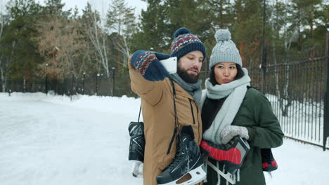couple taking a selfie while ice skating in the park on a snowy day