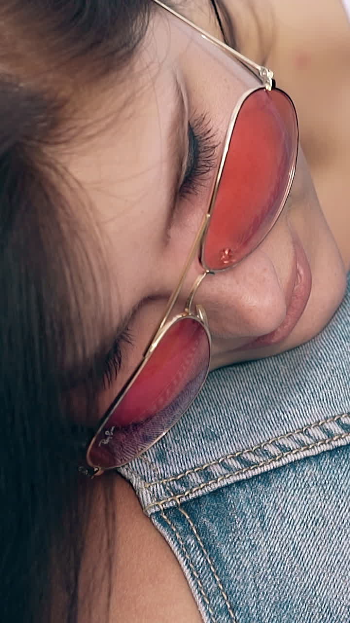 close view brunette lady in orange sunglasses puts head on man shoulder reflecting in black helmet
