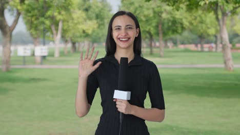 Happy-Indian-female-news-reporter-waving-Hello