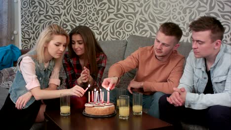 teen boy lighting a birthday candle on cake with friends at home