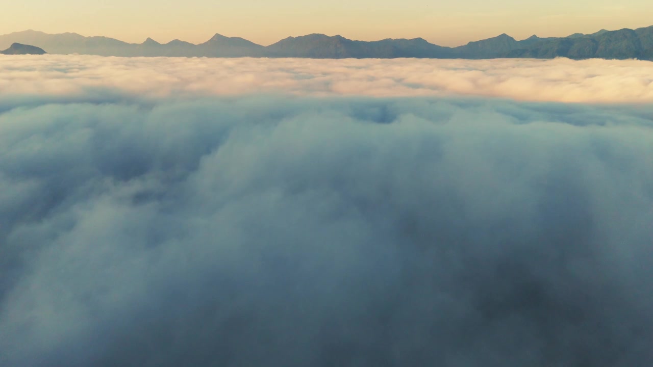 Aerial fly above clouds, sunset mountain background, slow natural rainforest skyline