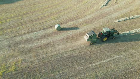 captura de órbita desplegable del tractor tirando de la empacadora de heno redonda detrás