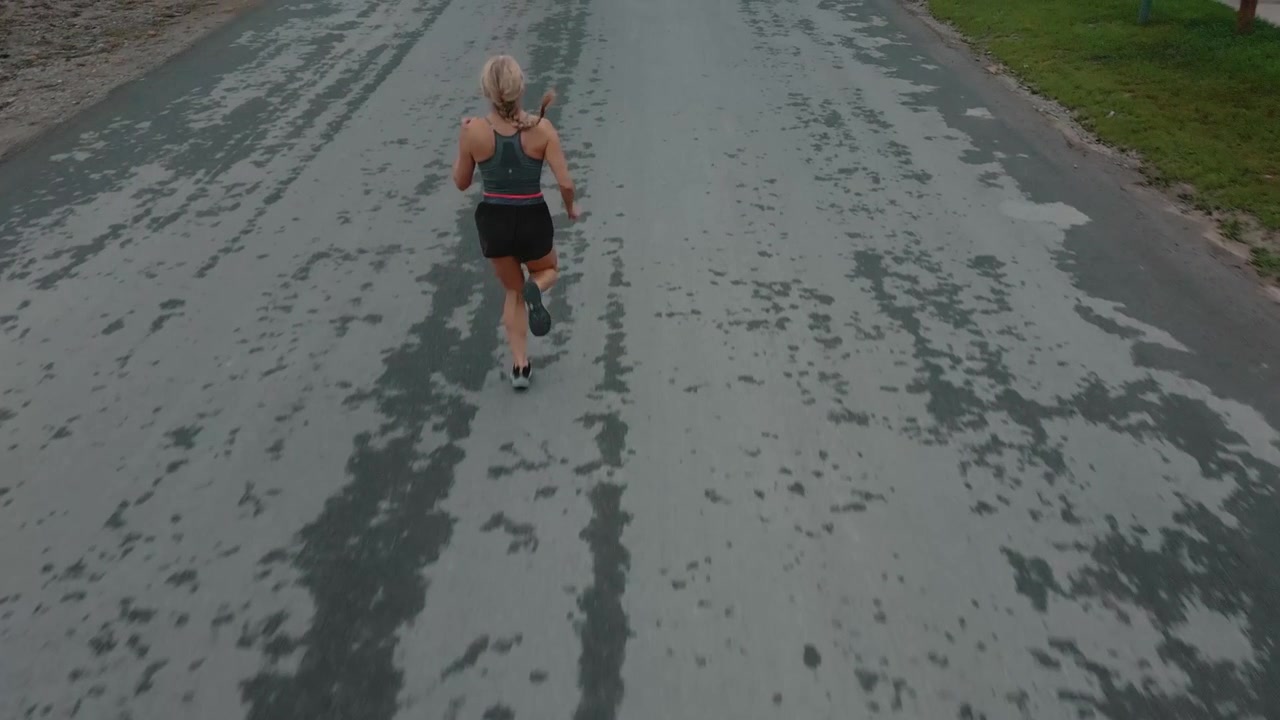 Giovane donna che fa jogging su una tranquilla strada suburbana