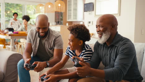 multi-generation male family sitting on sofa at home playing video game together