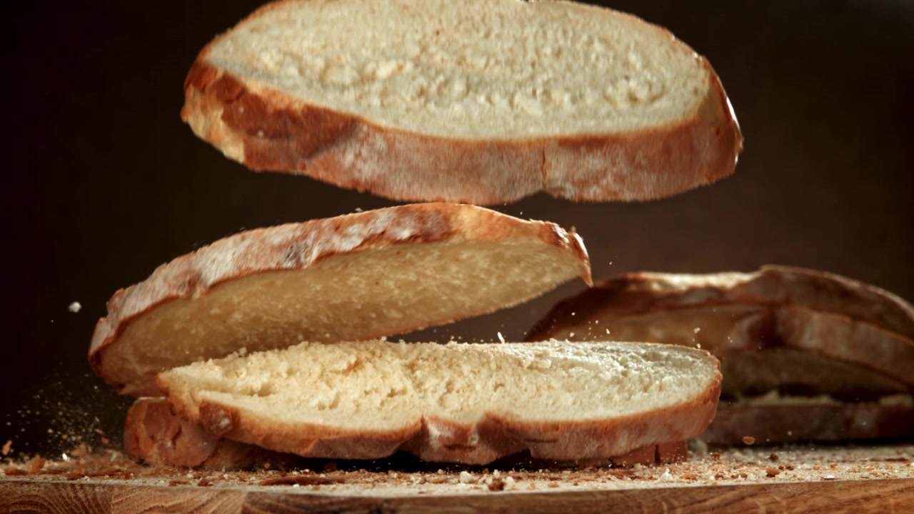 Movimento lento di fette di pane fresco che cadono e si impilano su un tagliere di legno
