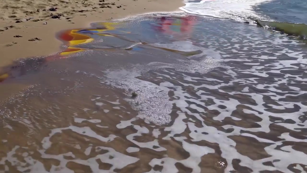 Ocean Waves Washing Over Sandy Beach with Colorful Umbrellas