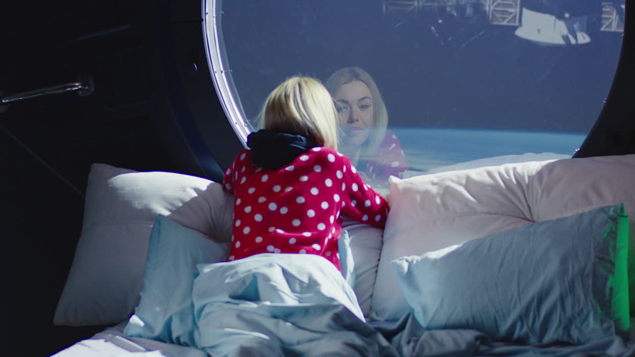 una mujer en una habitación de un hotel espacial mirando a la tierra.