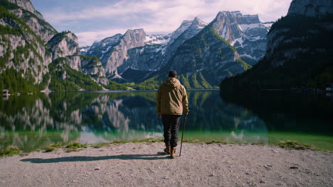 man standing by a lake, surrounded by mountains