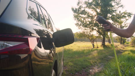 Man-plugging-in-the-charger-in-an-electric-car,-going-for-walk,-handheld-shot