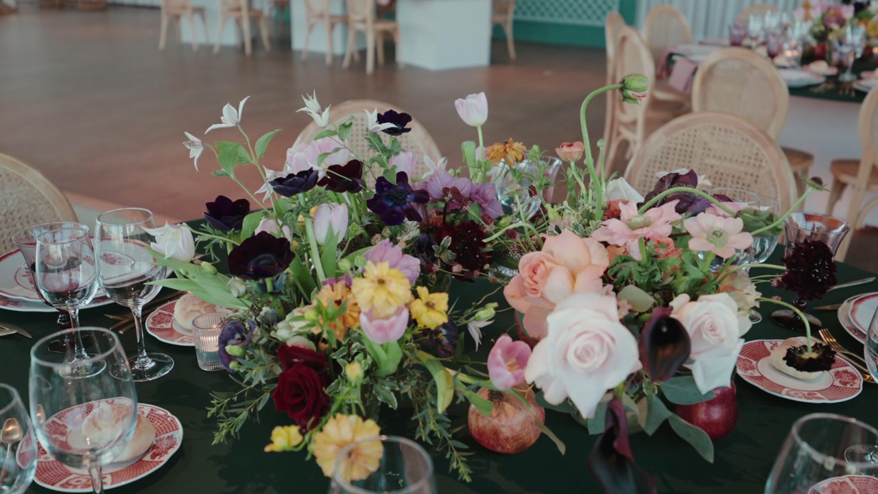 Decorated wedding table with colorful flowers glassware plates cutlery and candles arranged for reception