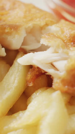 video close up of fish and chips with parsley and bowl of ketchup dip