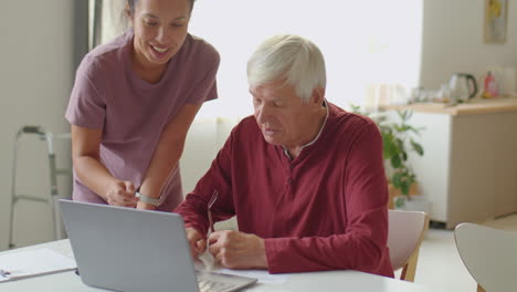 elderly man learning the internet with help of caregiver