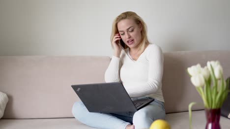 Female-freelancer-with-laptop-speaking-on-smartphone