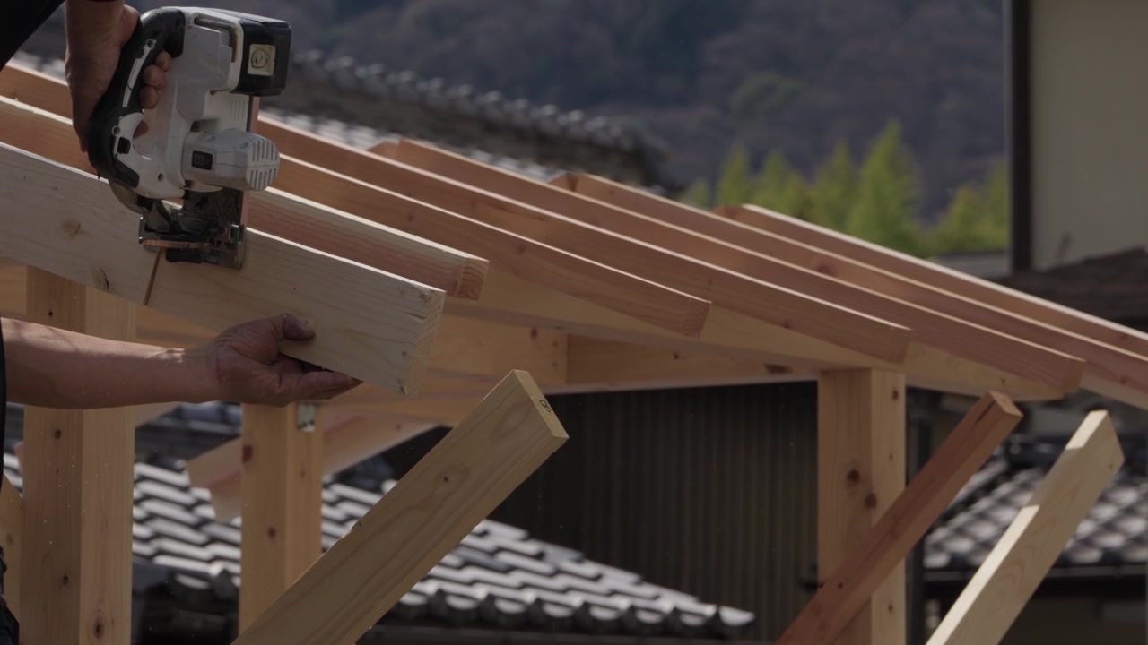 Falegname che usa una pistola sparachiodi su una costruzione di telaio di tetto in legno in Giappone