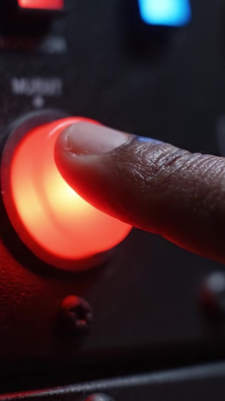 Primo piano di un pulsante rosso illuminato su un dispositivo elettronico, che evidenzia una funzione di controllo vitale con una sottile illuminazione di sfondo che ne esalta l'attrattiva visiva.