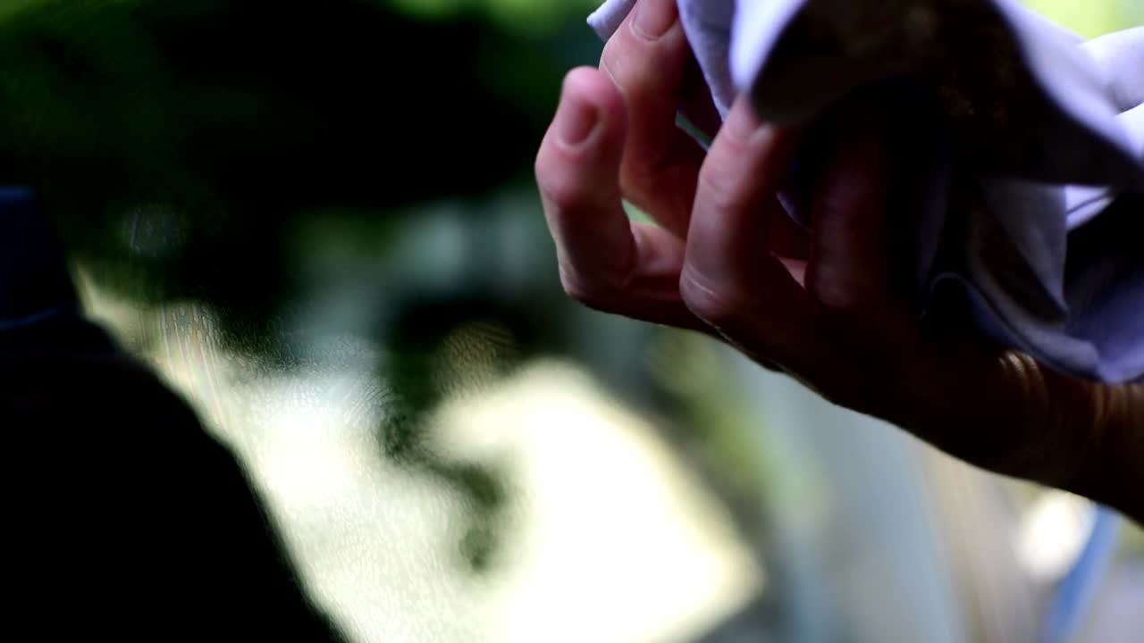 한 여성이 세차 후 낡은 천으로 차창을 닦고 있다