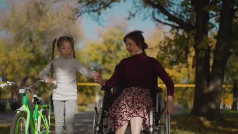 mother with legs injury walks with daughter in autumn park