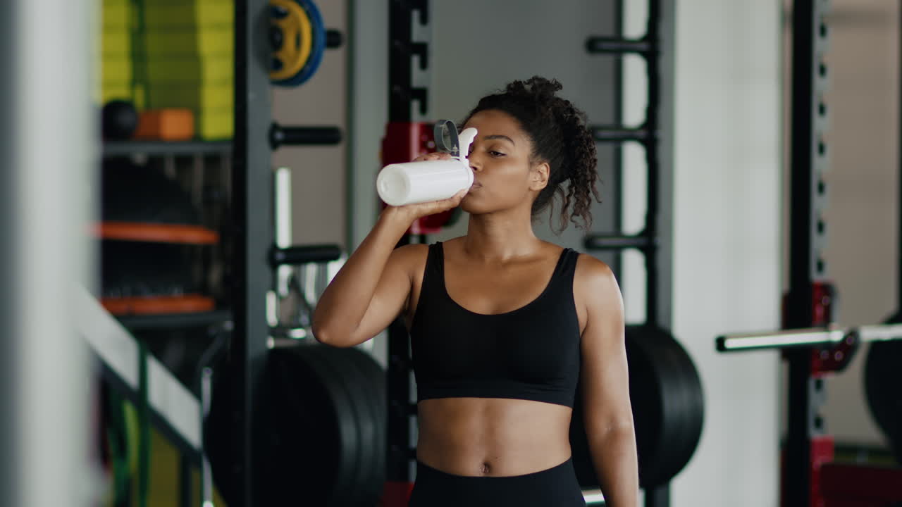 mujer bebiendo agua en el gimnasio