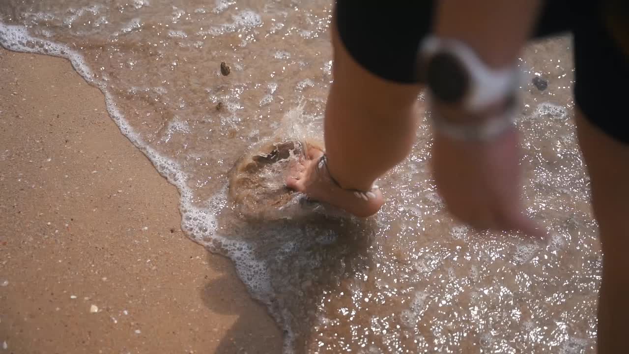 바다에서 파도가 태국에서 그녀의 발을 적시는 동안 여자는 해변에서 맨발로 걷는다