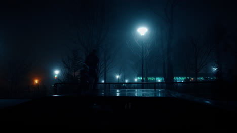 man and a little kid run in the darkness outdoors. father and child are in winter park in the light of street lamps.