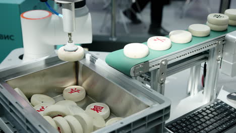 robotic arm sorting chinese chess pieces on a conveyor belt