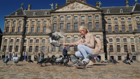 mujer está alimentando palomas en la plaza dam