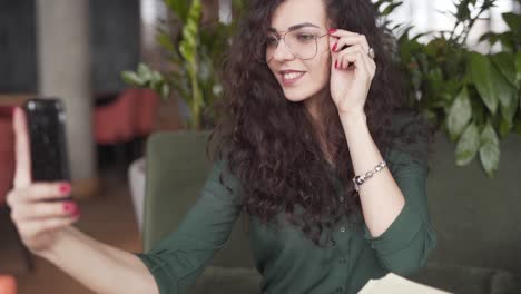 gorgeous young woman wearing glasses takes selfies inside a restaurant