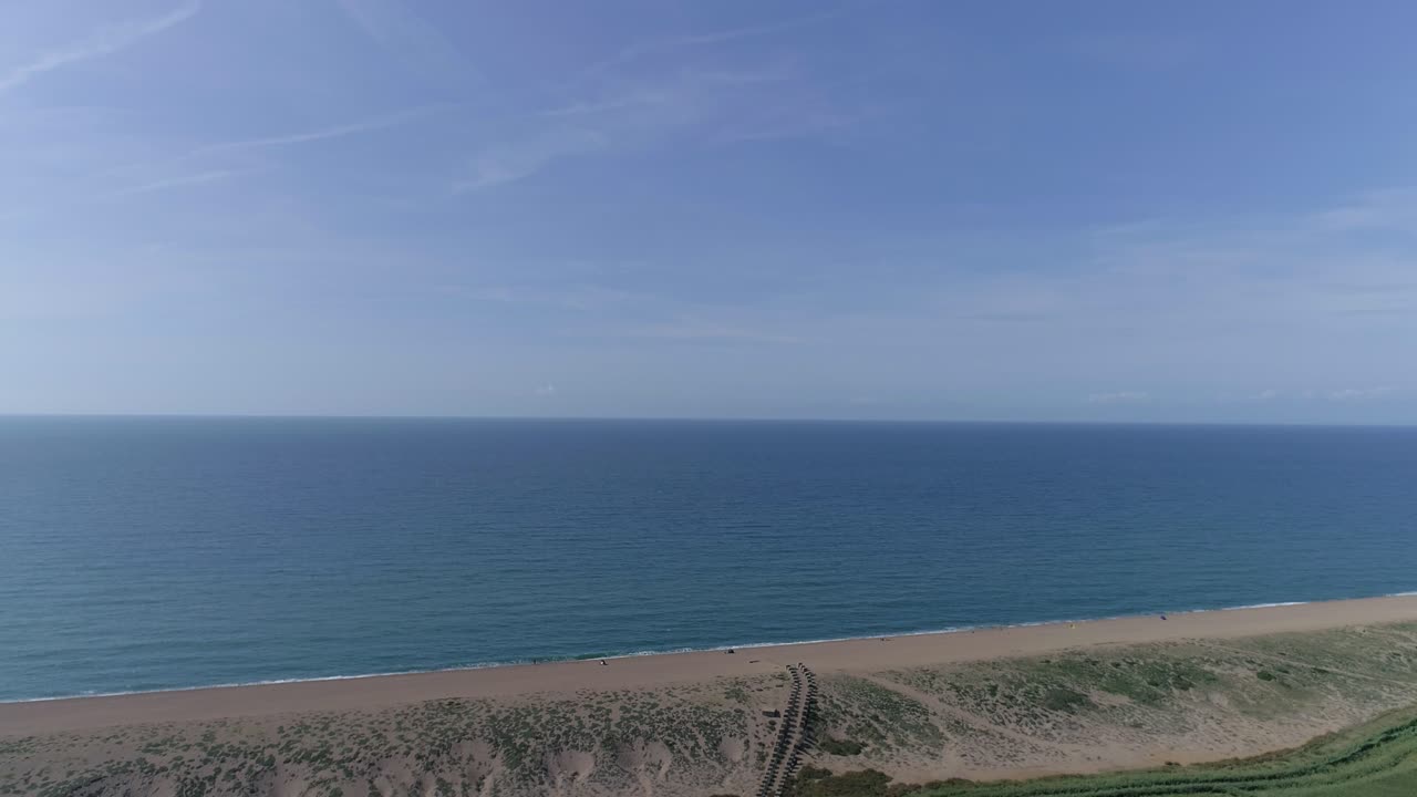 seguimiento aéreo hacia el hermoso cielo azul y el mar sobre una playa de guijarros con un lago inmediatamente en primer plano