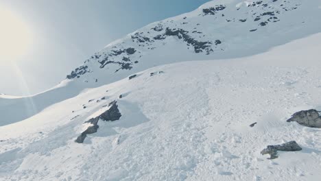 high snow covered mountain slope in norway with avalanche debris, aerial fpv view