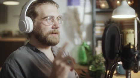 male blogger recording podcast in evening at home