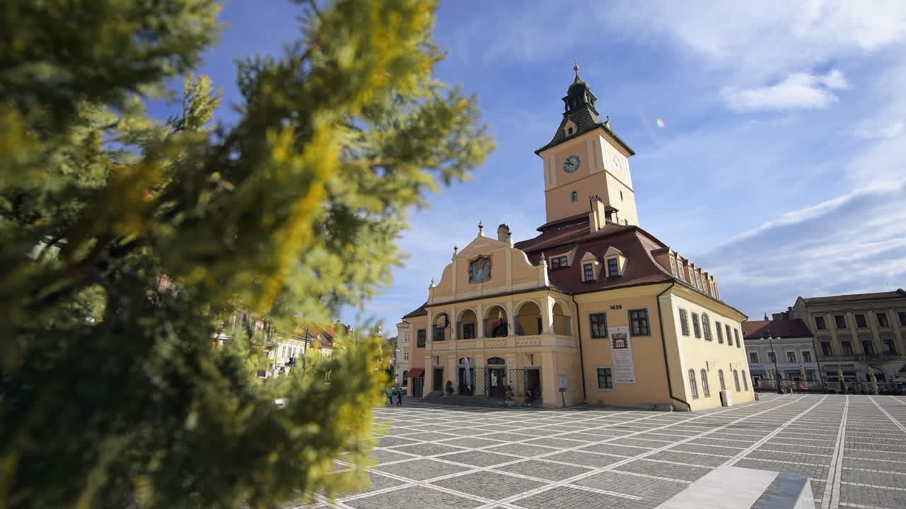 Udsigt over Rådhuspladsen i Brasov, Rumænien. Klassiske bygninger, gående mennesker og grønne områder