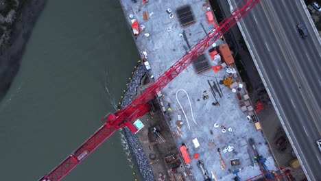 Crane-by-busy-highway-bridge-construction-zone-worker-from-above
