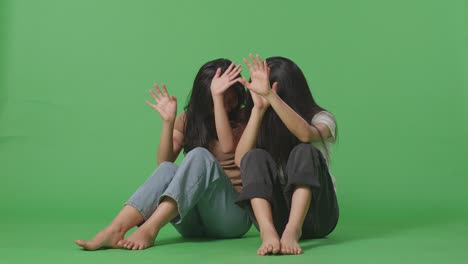 젊은 아시아 여성들의 몸은 폭력의 희생자입니다. 몸에 이 있습니다. 녹색 스크린 배경 스튜디오에 앉아서 방어하는 몸짓을 하고 두려워합니다.