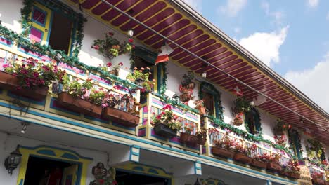 Colorido-Balcón-Con-Flores-Y-Banderas-De-Países-En-Un-Albergue-En-Salento,-Colombia