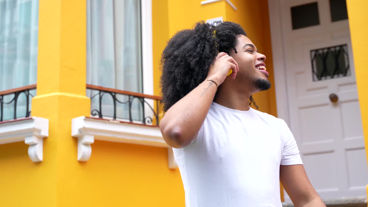 Man with Afro and Headphones Dancing in Front of Yellow House