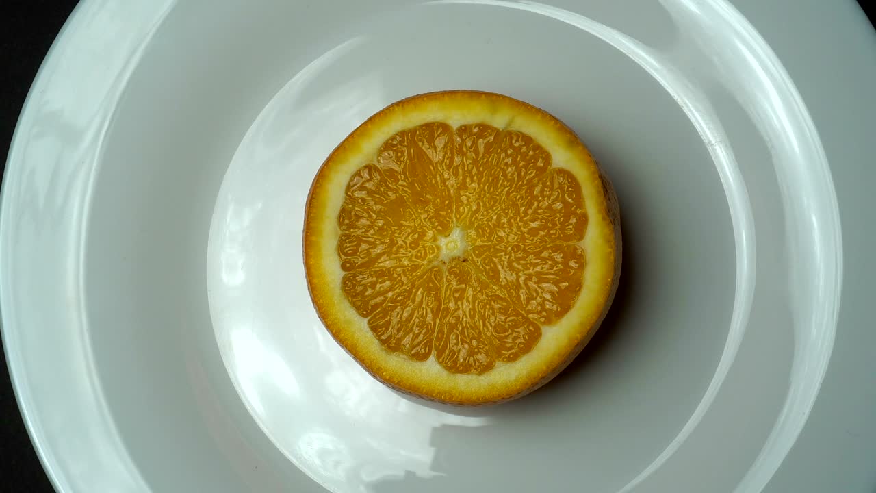 Arancia fresca che si ingrandisce e ruota sul piatto bianco